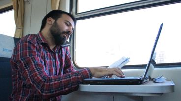 Un periodista trabaja arriba del tren. Importante: hay enchufes para cargar aparatos electrónicos.