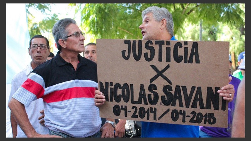 Un hombre sostiene un cartel en pleno reclamo.