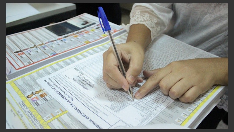 Un presidente de mesa marca en la lista a una persona.