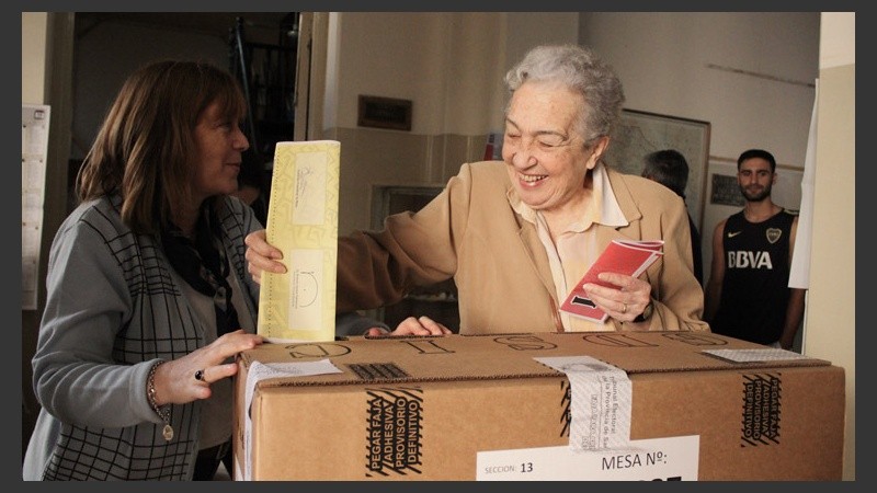 Una señora sonríe ante la cámara mientras vota.