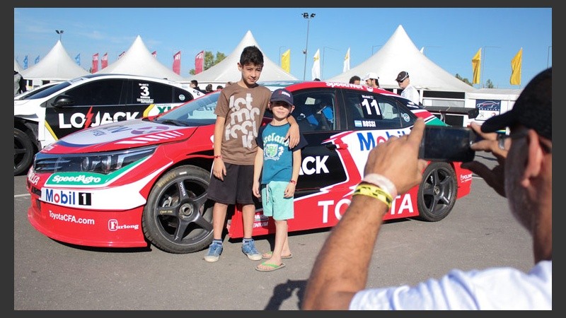 Unos pequeños se sacan una foto con un auto detrás.