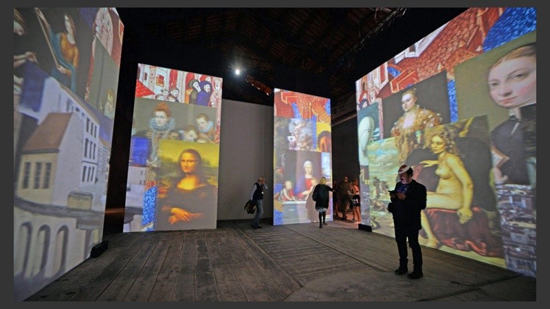 Varias personas contemplan una obra en formato audiovisual del artista británico Peter Grennaway.