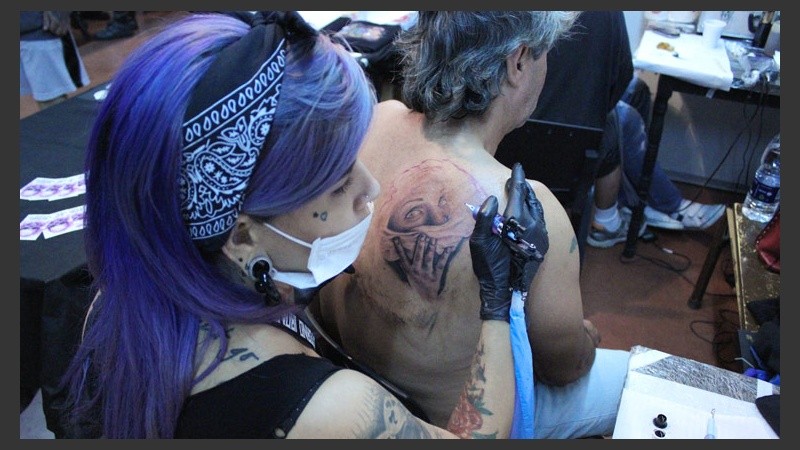 Una joven plasma el rostro de una mujer en la espalda de un hombre.