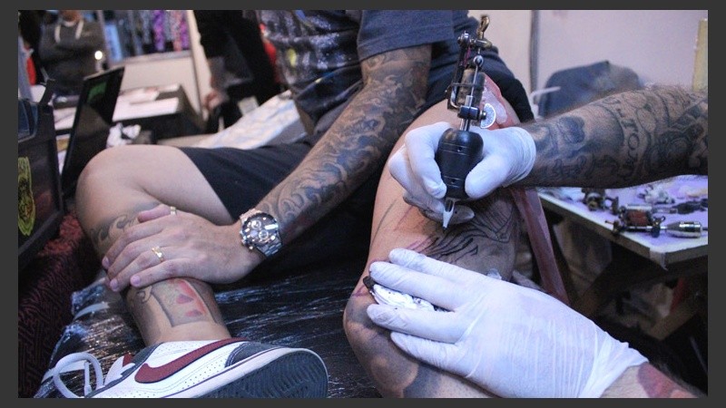 Un chico resiste al dolor mientras es tatuado en su pierna izquierda.