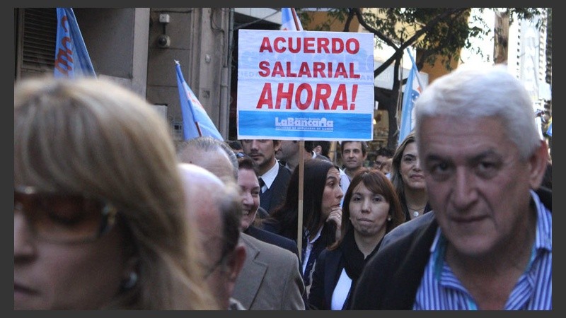 Una mujer sostiene un cartel pidiendo un aumento de salario.