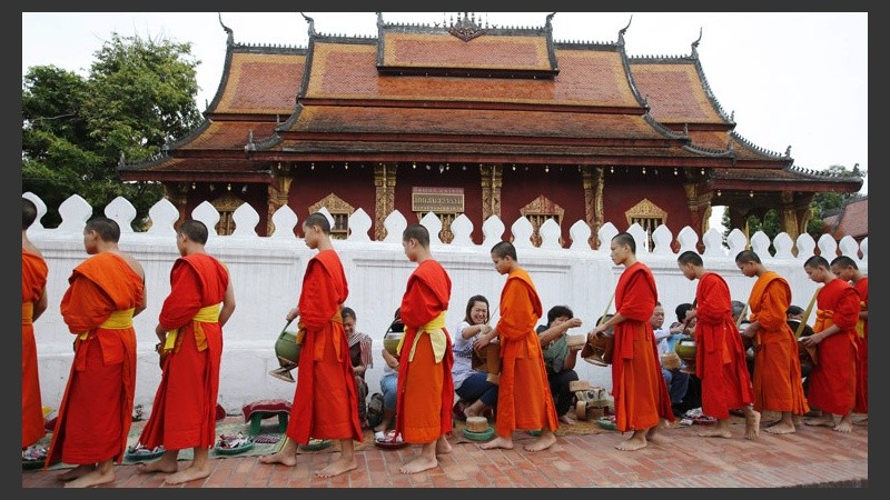 Monjes budistas en contacto con turistas en un ritual que se realiza diariamente en una ciudad de Laos.