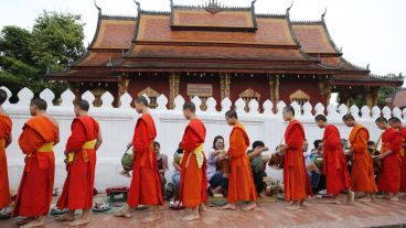 Monjes budistas en contacto con turistas en un ritual que se realiza diariamente en una ciudad de Laos.