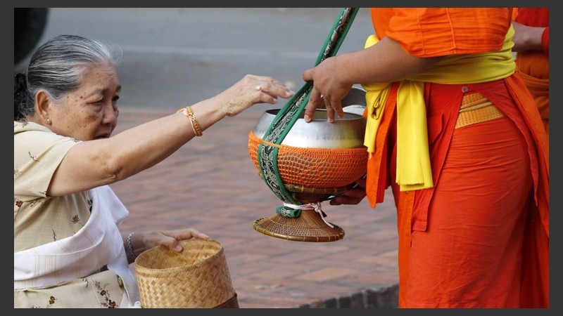 Una mujer le otorga una ofrenda a los monjes.