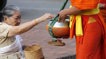 Una mujer le otorga una ofrenda a los monjes.