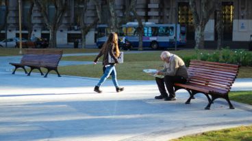 Un señor lee el diario en los nuevos bancos de madera.
