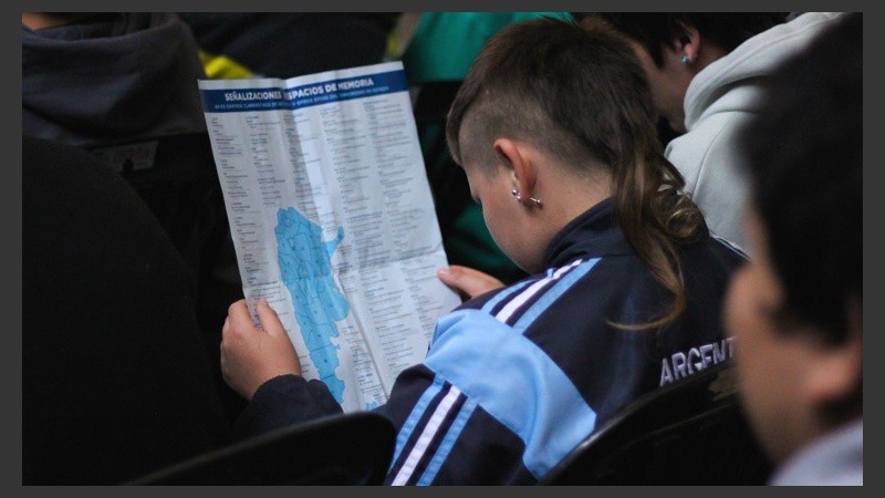 Un alumno se informa con un folleto que repartieron en el acto.