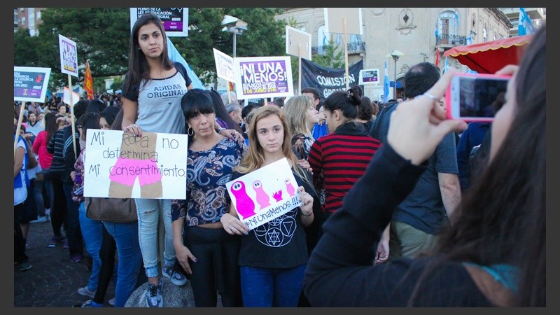 Tres mujeres posan ante cámara mostrando sus carteles.
