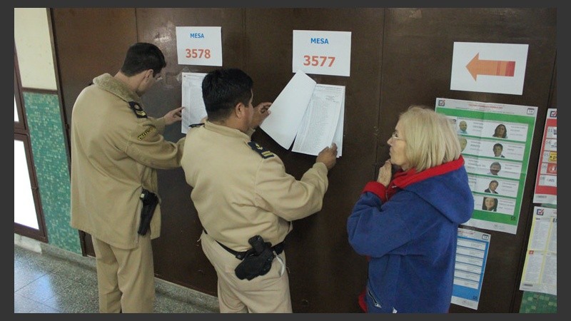 Personal de Prefectura ayuda a buscar la mesa a una señora.