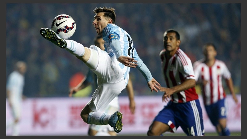 Messi baja la pelota en el área chica en una postura acrobática. (EFE)