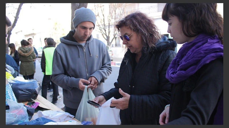 Una mujer deja su donación mientras los ayudantes la observan con atención. (Rosario3.com)