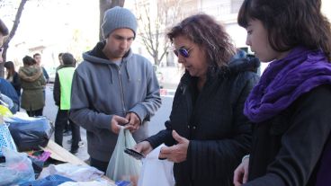 Una mujer deja su donación mientras los ayudantes la observan con atención. (Rosario3.com)
