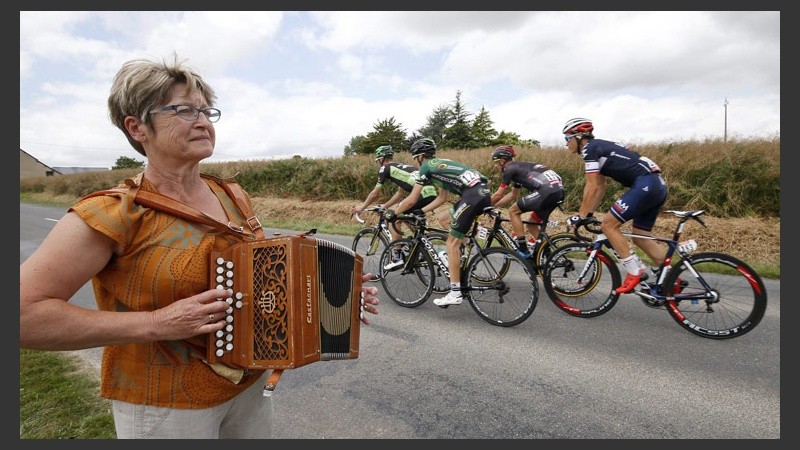 Una mujer toca un instrumento durante una pasada de ciclistas en la octava etapa. (EFE)
