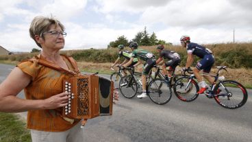 Una mujer toca un instrumento durante una pasada de ciclistas en la octava etapa. (EFE)