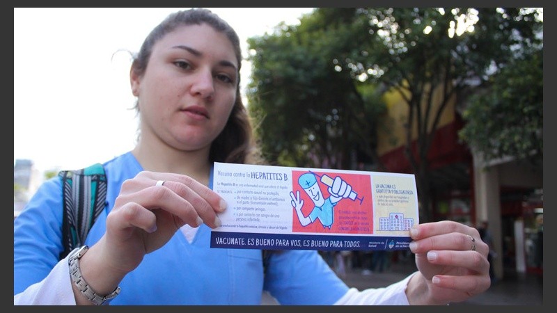 Una de las voluntarias muestra un folleto que invita a participar de la jornada de vacunación. (Rosario3.com)