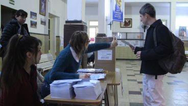 Una autoridad de mesa indica dónde poner el sobre a un elector. (Rosario3.com)