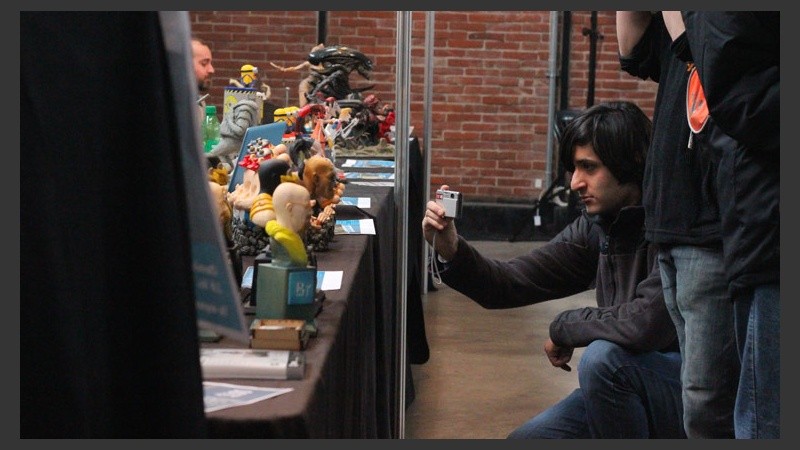 Un joven le saca una foto a uno de los muñecos artesanales. (Rosario3.com)