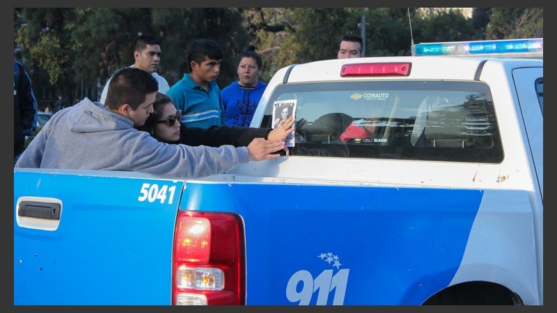 Dos jóvenes pegan un cartel en uno de los móviles policiales que circulaban por el lugar. (Alan Monzón/Rosario3.com)