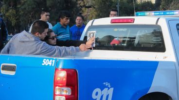 Dos jóvenes pegan un cartel en uno de los móviles policiales que circulaban por el lugar. (Alan Monzón/Rosario3.com)