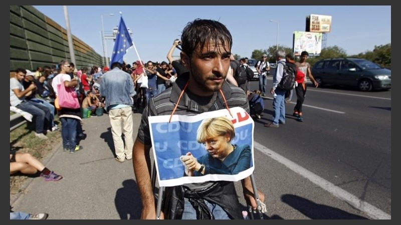 Un húngaro se cuelga el cartel de Merkel para aumentar sus chances de entrar. 