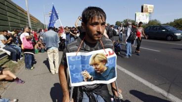 Un húngaro se cuelga el cartel de Merkel para aumentar sus chances de entrar.