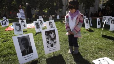 Una niña observa fotos de desaparecidos durante la dictadura. (EFE)