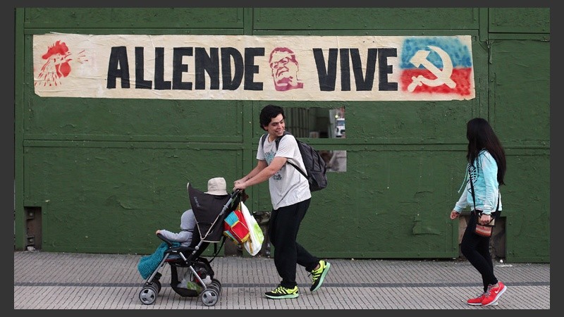 Una familia pasa delante de un cartel que recuerda a Allende. (EFE)