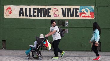 Una familia pasa delante de un cartel que recuerda a Allende. (EFE)