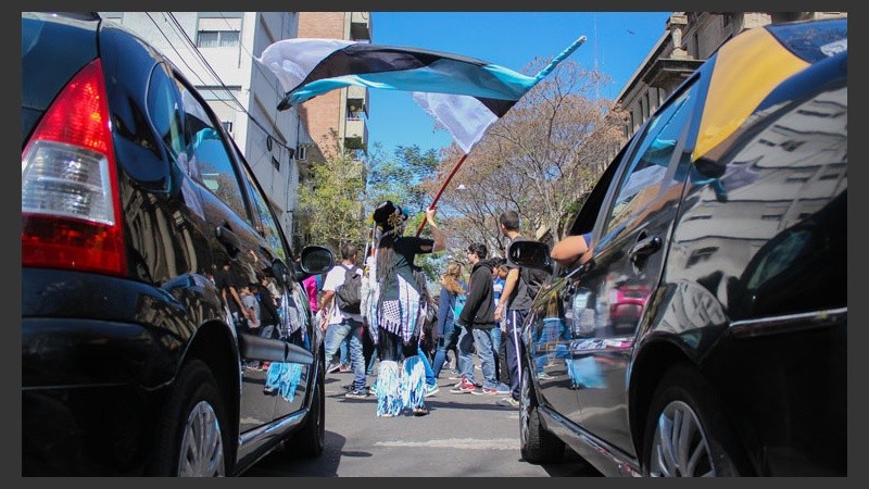 Una chica murguera flamea una bandera ante la espera de los vehículos. (Alan Monzón/Rosario3.com)