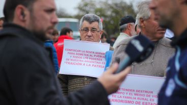 Un hombre muestra un cartel mientras el periodista Pedro Levy realiza una entrevista. (Alan Monzón/Rosario3.com)