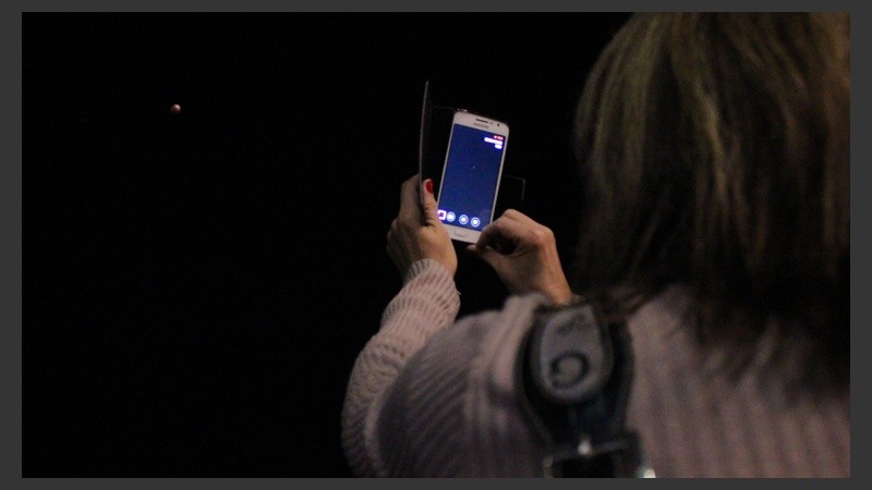 Una mujer le saca una foto a la Luna roja con su celular. (Rosario3.com)