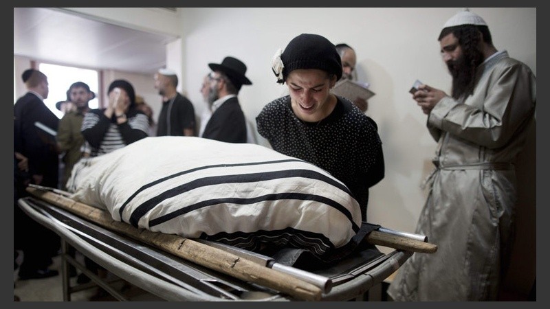 Una mujer junto a uno de los cuerpos durante el funeral judío en Jerusalén. (EFE)