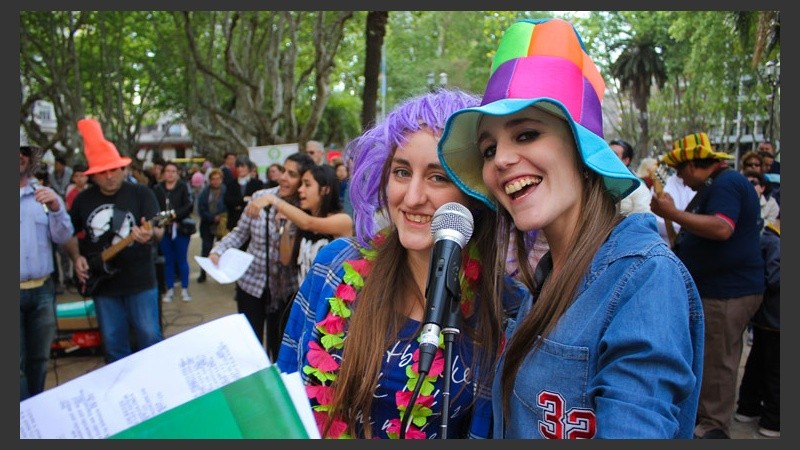 Dos chicas sonríen ante cámara durante la interpretación de una canción frente a la Catedral. (Alan Monzón/Rosario3.com)