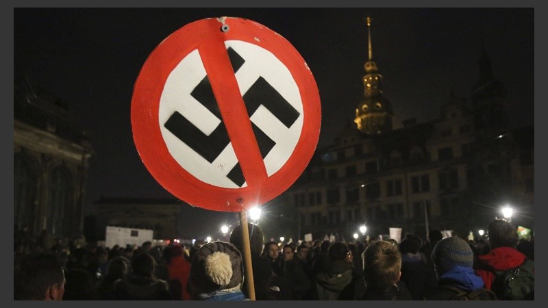 Un activista del movimiento islamófobo sujeta un cartel con una cruz esvástica tachada durante la manifestación de este lunes por la noche. (EFE)