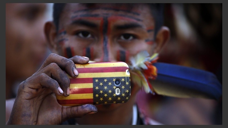 Un hombre mira a cámara con su celular con la bandera de Estados Unidos. (EFE)