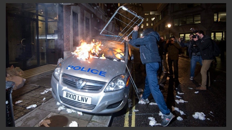 Un manifestante destroza un auto de la policía. (EFE)