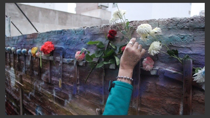 Una mujer pone unas flores en las cruces que recuerdan a las víctimas. (Alan Monzón/Rosario3.com)