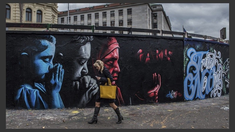 Una mujer camina junto a un grafiti que conmemora a las víctimas realizado por el artista kazajo 