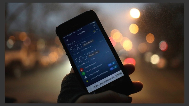 Un hombre sostiene un celular en el que muestra una app que indica la alta concentración de partículas en Pekín. (EFE)