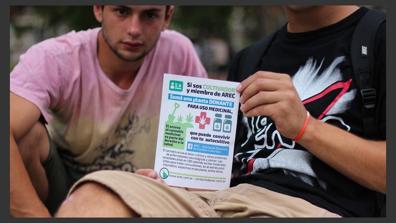Unos jóvenes muestran uno de los folletos que se repartieron en la movilización a favor del cannabis. (Alan Monzón/Rosario3.com)