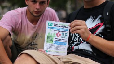 Unos jóvenes muestran uno de los folletos que se repartieron en la movilización a favor del cannabis. (Alan Monzón/Rosario3.com)