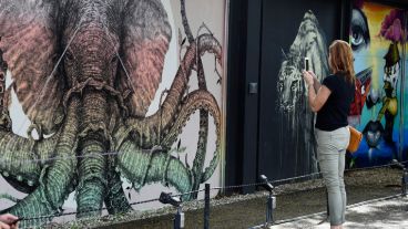 Una mujer toma una fotografía de un mural. (EFE)