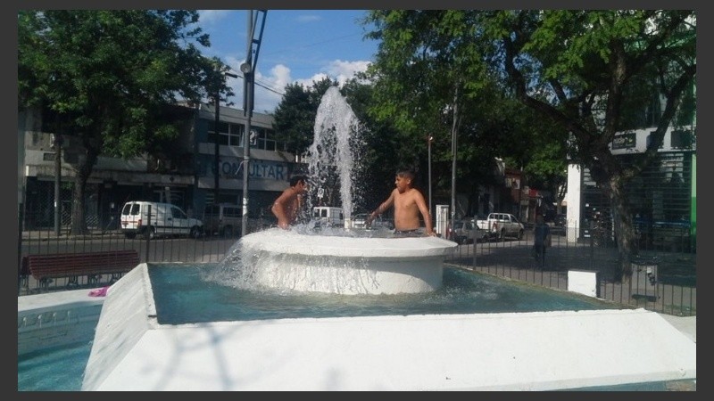 Dos chicos combaten el calor jugando en una fuente de San Martín y Ayolas.