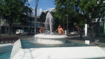 Dos chicos combaten el calor jugando en una fuente de San Martín y Ayolas.