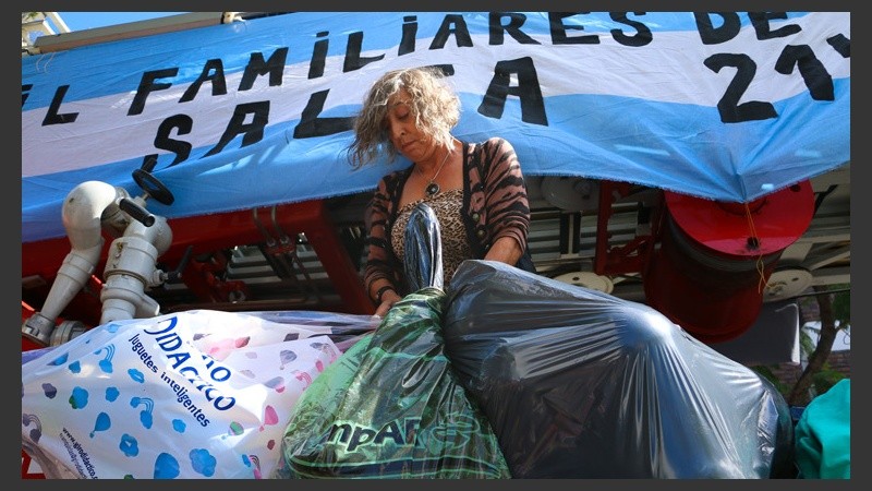 Una voluntaria sube bolsas con regalos a la autobomba. Hubo muy buena respuesta de la gente para colaborar con la causa. (Rosario3.com)