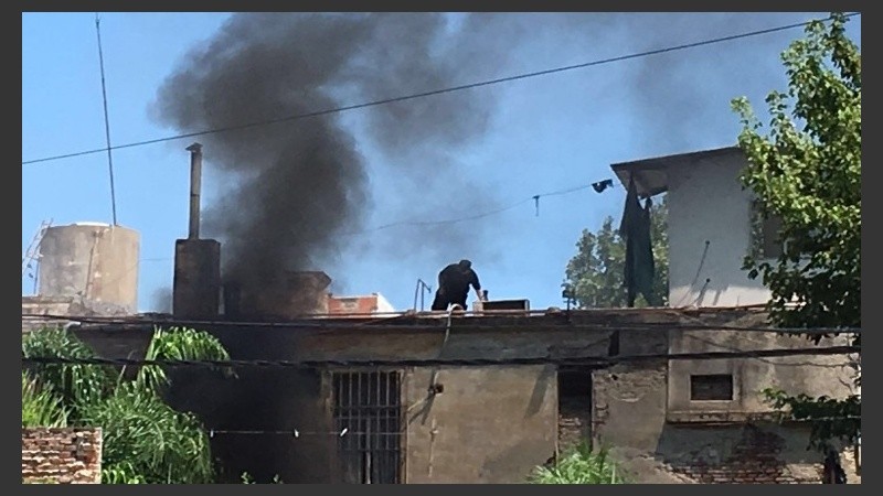 Despliegue policial en los techos. De fondo, humo de colchones quemados.